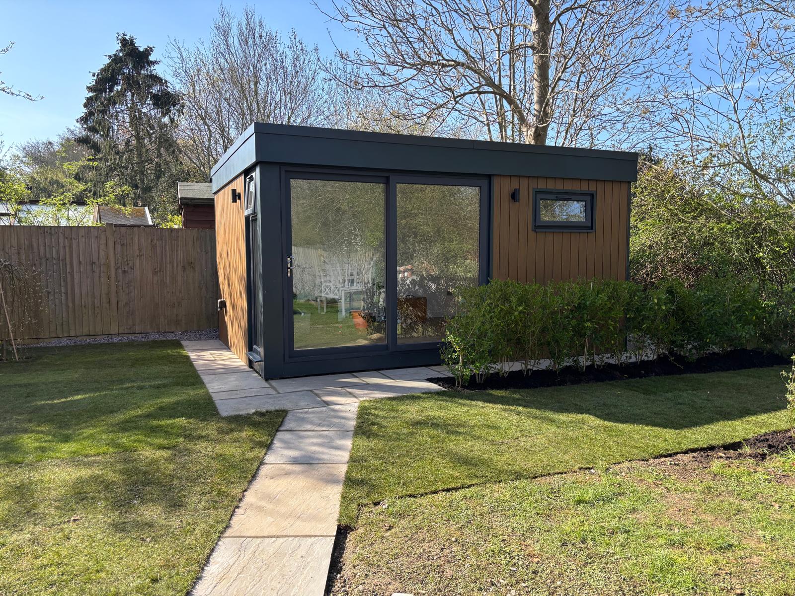 Modern composite garden room with wood-like finish and large glass sliding doors