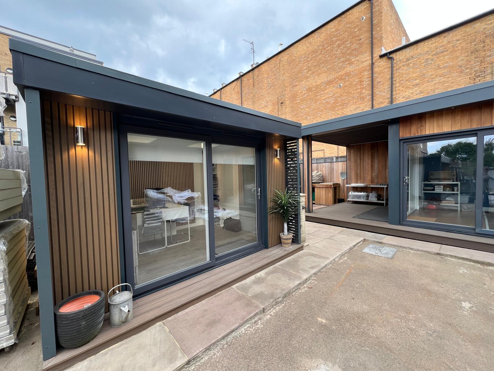 Two adjacent garden rooms with vertical composite paneling in warm wood tone
